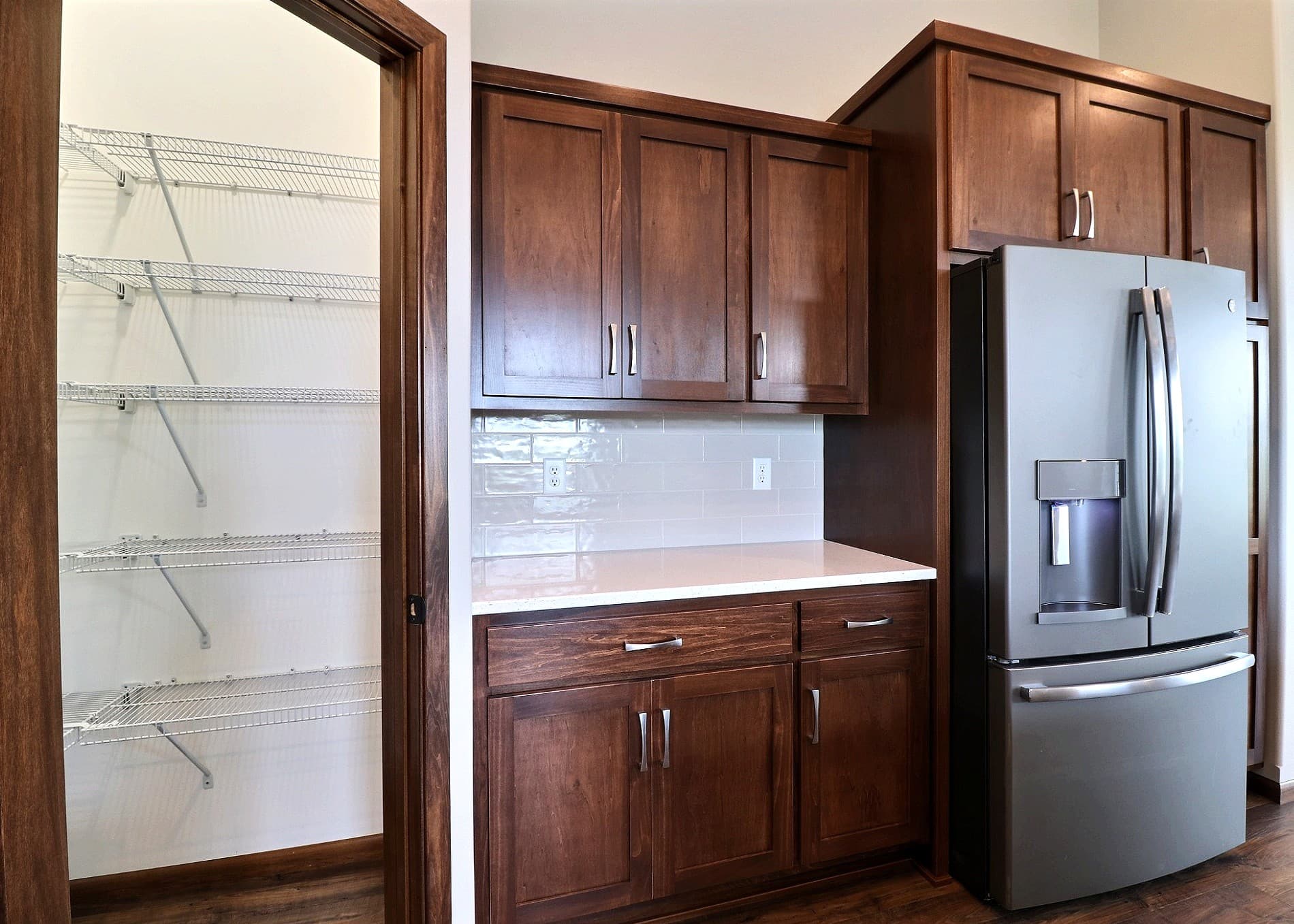 Cherry kitchen cabinetry with subway tile backsplash and walk-in pantry